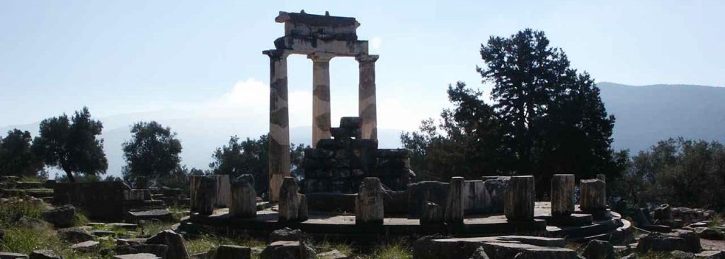 Delphi: Three restored columns amid other stone ruins atop a hill